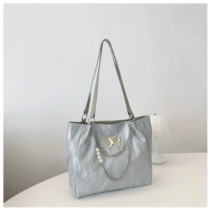 Detail of silver tote bag with pleated texture, butterfly charm and pearl chain