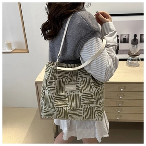Detail of green geometric jacquard tote bag with white leather strap and fashion label