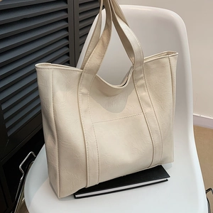Creamy white pebbled leather tote bag for women placed on a stylish Nordic chair
