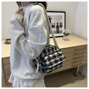 Detail of checkered crossbody bag with heart pattern and adjustable white strap