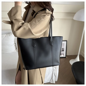 Schicke schwarze matte Leder-Tote-Bag mit vertikalen Nähten am Modell in modernem Interieur