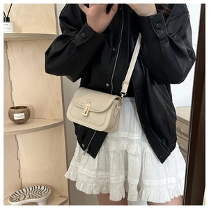 Detail of cream crossbody bag with golden twist lock worn with black leather jacket