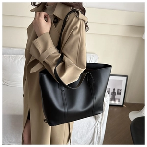 Minimalistische schwarze Einkaufstasche aus mattem Kunstleder mit einem khakifarbenen Trenchcoat