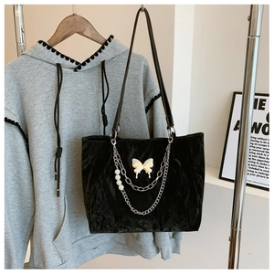 Detail of black pleated tote bag with silver butterfly pendant and pearl chain decoration