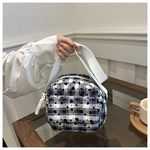 Close-up of black and white plaid mini crossbody bag with heart pattern and wide strap