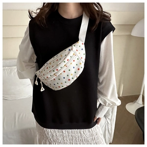 Detailed view of white polka dot canvas chest bag with adjustable nylon strap and zippers