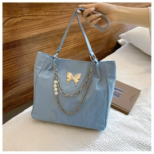 Close-up of light blue pleated tote with gold butterfly hardware and pearl chain charm