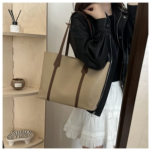 Schicke beige Tragetasche mit schmalen braunen Riemen als stilvolles Pendler-Accessoire