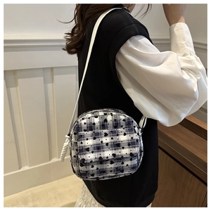 Detail of plaid crossbody bag featuring small heart patterns and white rope strap