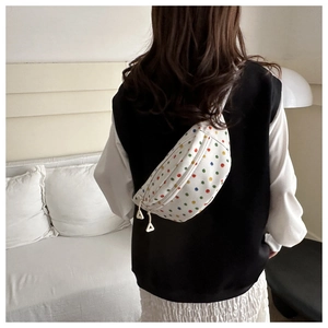 Detailed back view of a white canvas chest bag with vibrant colorful polka dots on a model