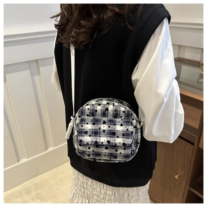 Detail of a round canvas crossbody bag with black and white checkered heart pattern