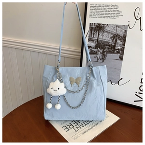 Detail of light blue tote bag with metallic chain and silver butterfly ornament