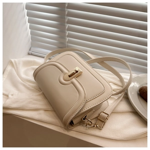 Close-up of cream small square bag with golden U-shaped lock and fine faux leather texture