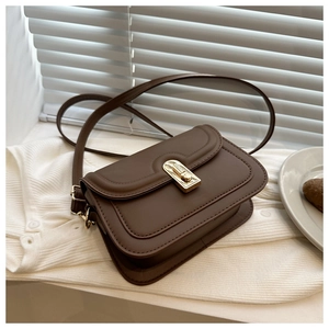 Detail of retro brown small square bag with golden lock on a white sweater background