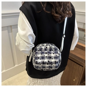 Detail of blue and white plaid crossbody bag with black hearts and adjustable strap