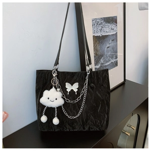 Close-up of black pleated tote bag with silver chains and white butterfly detail