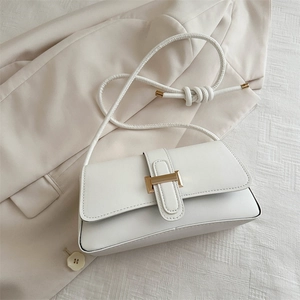 Elegant white leather baguette shoulder bag with gold buckle on beige blazer