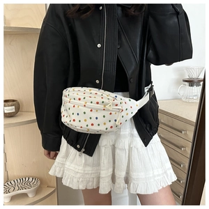 Close-up of white canvas waist bag with colorful polka dots worn across a leather jacket