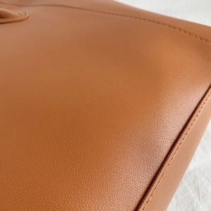 Brown leather tote bag with lychee texture and stitching detail on white background