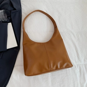 Minimalist caramel brown leather tote bag with wide strap on professional office attire