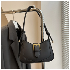 Gros plan sur le sac sous le bras en cuir noir avec boucle dorée et détail de nœud