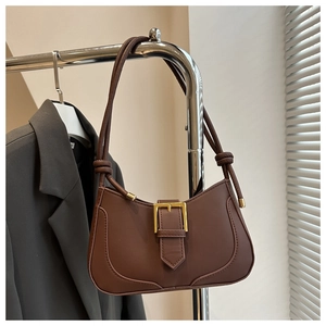 Détail du sac croissant en cuir mat marron avec boucle dorée et bandoulière à nœuds