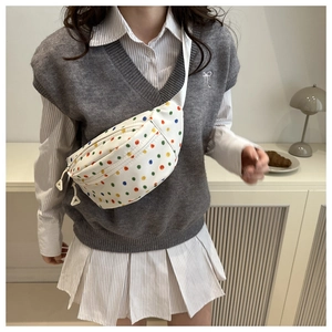 Detailed close-up of a white canvas waist bag featuring colorful polka dot patterns