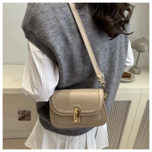 Detail of beige faux leather crossbody bag with gold metal twist lock and adjustable strap