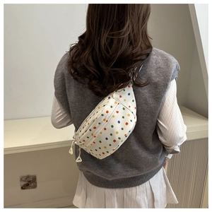 Detailed back view of a white nylon crossbody bag featuring colorful polka dots and zippers