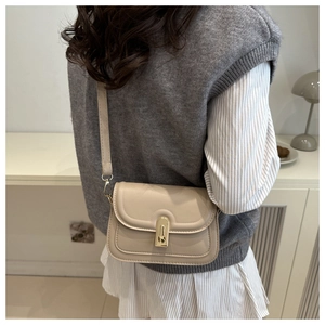 Detail of beige flap crossbody bag with golden metal buckle clasp on minimalist background