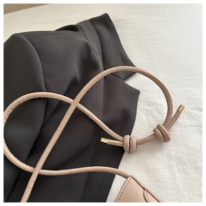 Détail de la bandoulière en cuir nude avec nœud décoratif et finitions dorées