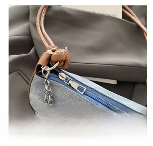 Détail du sac en denim bleu avec nœud argenté, perles et fermeture éclair fluide