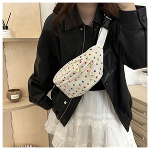 Detail of white canvas crossbody bag with multi-color dots and adjustable strap