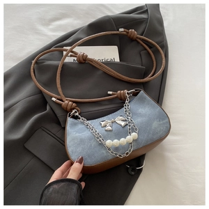 Detail of denim and leather shoulder bag with silver bow, chains and pearl accents