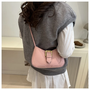 Détail du sac sous l'aisselle en cuir rose avec boucle dorée sur l'épaule du modèle