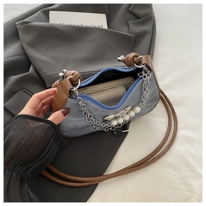 Detail of denim and leather shoulder bag featuring silver chain and pearl accents