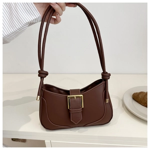 Détail d'un sac à bandoulière marron en similicuir avec boucle dorée et sangle nouée