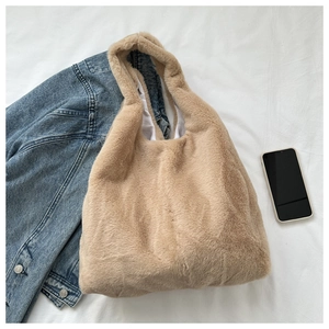 Mise à plat d'un sac cabas en peluche sur tissu blanc à côté d'une veste en jean
