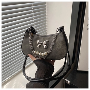Détail macro du sac demi-lune en denim gris foncé avec nœud argenté et chaîne perle