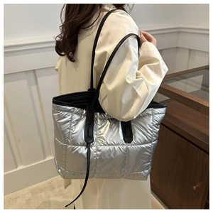 Detail of silver quilted tote bag with black leather straps for commute and fashion