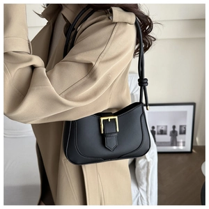 Détail d'un sac baguette noir mat avec boucle dorée et bandoulière nouée sur modèle
