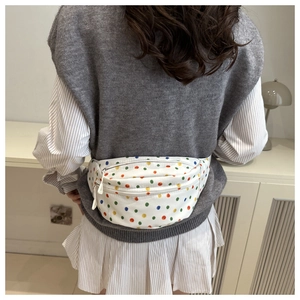 Detailed view of a white canvas waist bag featuring colorful polka dots worn by a model
