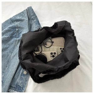 Vue intérieure montrant la grande capacité du sac fourre-tout en peluche noir et objets