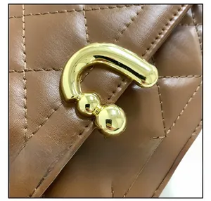 Macro shot of brown quilted leather texture and gold U-shaped hardware clasp on bag