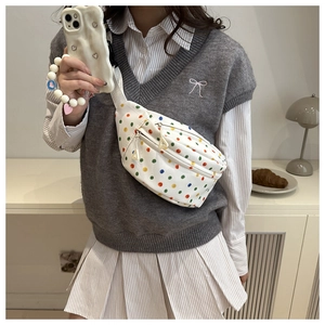 Close-up of white crossbody bag with colorful polka dots and double zipper detail