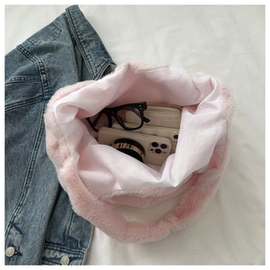 Grand sac cabas rose en peluche montrant les objets du quotidien sur un drap blanc