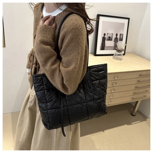 Detailed view of black quilted puffer tote bag on a model for daily autumn styling
