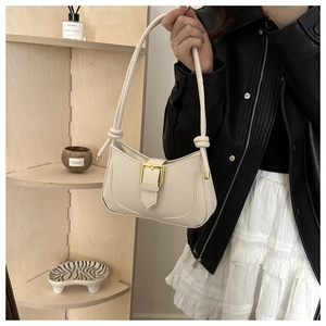 Détail du sac beige en demi-lune avec boucle dorée et bandoulière nouée élégante