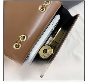 Detail showing inner capacity of brown quilted chain bag with phone and cosmetics