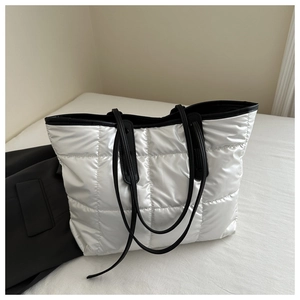 Close-up of silver quilted tote bag with black straps and metallic grid texture